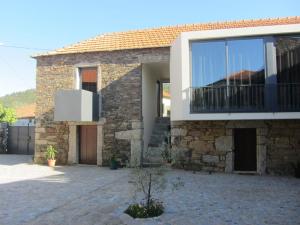 a brick house with a large window and a balcony at Casa do Villas in Castelo de Paiva