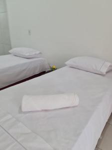 two beds with white sheets and towels on them at Pousada Jereissati in Maracanaú