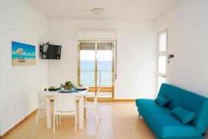 uma sala de estar com uma mesa e um sofá azul em Casa sul mare vicino Marina di Ragusa em Villaggio Azzurro
