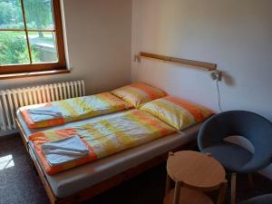 ein kleines Schlafzimmer mit einem Bett und einem blauen Stuhl in der Unterkunft Penzion Hvozd in Nová Pec