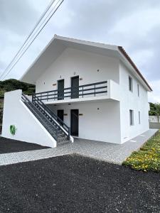 a white house with a staircase in front of it at Apartamentos 4 estações in Faja Grande