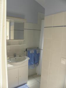 a white bathroom with a sink and a mirror at La Parenthèse in Sommières