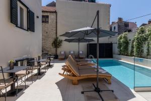 einen Pool mit Tischen, Stühlen und einem Sonnenschirm in der Unterkunft Sperone Hotel in Split