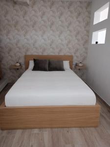 a bedroom with a bed with white sheets and a wall at La Lunita in Valverde