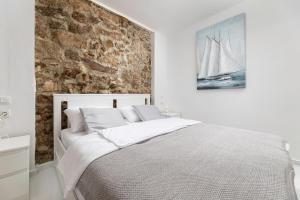 um quarto com uma cama branca e uma parede de tijolos em Apartment GAVIOTA Krk em Krk