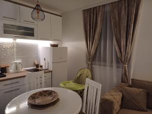 una pequeña cocina con mesa, mesa y sillas en Apartman Silver Lux Srebrno jezero, en Veliko Gradiste