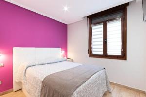 1 dormitorio con cama y pared púrpura en A tan solo 800 metros de San Mamés, en Bilbao