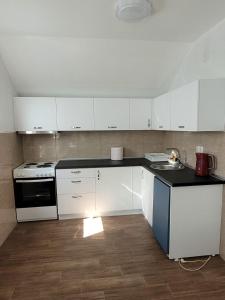 a kitchen with white cabinets and a stove and a sink at Odmorište Vrelo Vape in Sjenica