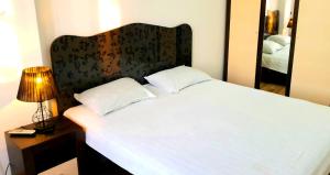 a bedroom with a white bed with a headboard and a lamp at Stylish apartment in the city center in Bishkek