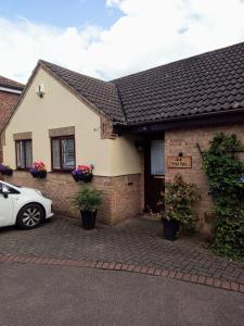 una casa con un coche aparcado delante de ella en Cosy room with 3 bed spaces in a friendly bungalow en Bletchley