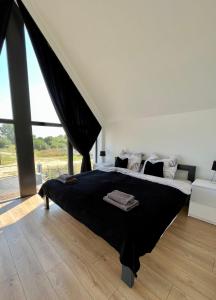 a bedroom with a large bed and a large window at Szklane Domki Ińsko in Ińsko