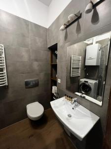 a bathroom with a sink and a toilet and a mirror at Lux apartmenty - Old City Kraków in Krakow