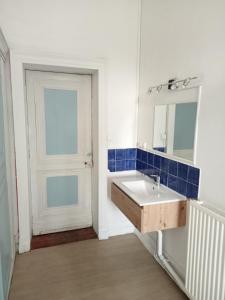 een badkamer met een wastafel, een spiegel en een deur bij 1812 Route de Baziège à Labège in Labège