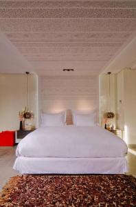 a bedroom with a large white bed with a rug at Cesar Resort & Spa in Marrakesh