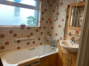 a bathroom with a tub and a sink and a window at Main Street 2 bedroom town house in Llandeilo