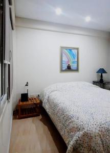 1 dormitorio con 1 cama y una pintura en la pared en Akum en Ushuaia