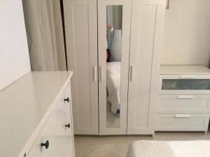 a white bedroom with white cabinets and a mirror at Apartman Martini in Orikum
