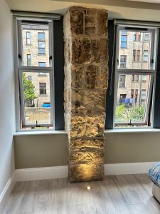 um quarto com duas janelas e uma parede de pedra em Glasgow West End Tenement Apartment em Glasgow