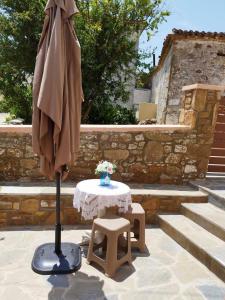 une table avec un parasol et une table avec un tabouret dans l'établissement Elisavet Room Portiano, à Pedhinón