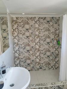 baño con lavabo blanco y pared estampada en Elisavet Room Portiano en Pedhinón