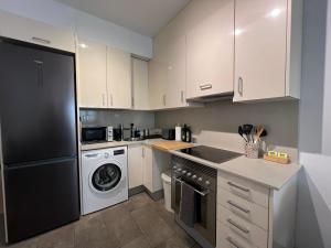 a kitchen with white cabinets and a black refrigerator at Cozy apartment well-located in Terrassa, Barcelona in Terrassa