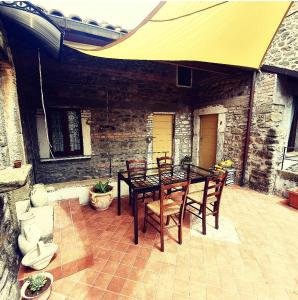 een patio met een tafel en stoelen en een gele parasol bij Affittacamere Dodo in Villafranca in Lunigiana