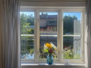 un jarrón de flores sentado en un alféizar de la ventana en Lovely Waterfront Cottage near Karlshamn en Asarum