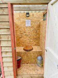 a sauna with a wooden toilet in a brick wall at Robin Goch Retreat in Carmarthen