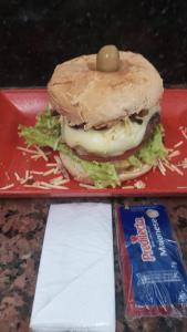 uma sanduíche num tabuleiro vermelho com um saco de batatas fritas em Motel Cigano’s em Belo Horizonte