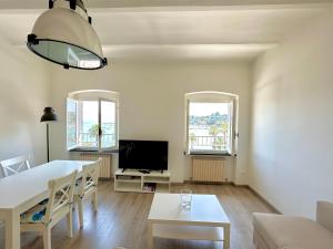 a living room with a dining room table and two windows at Maison Mazzini48 in Rapallo
