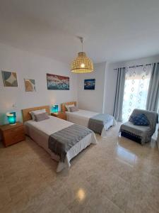 a bedroom with two beds and a couch and a chandelier at T2 Vila Atlântida Praia Vilamoura in Quarteira