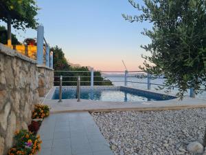 a swimming pool next to a stone wall next to the water at Villa sea oasis Ratac in Slano