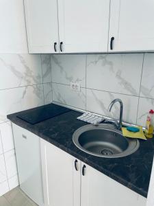 a kitchen counter with a sink and white cabinets at Elma in Dobra Voda