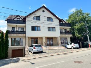 une maison blanche avec deux voitures garées devant elle dans l'établissement STUDIO POIENII - a cozy stay 5 min away from the center, à Bistriţa