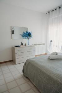 a white bedroom with a bed and a dresser at Casa vacanze La Farfalla in San Vito Chietino