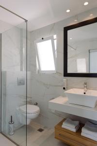 a bathroom with a sink and a toilet and a mirror at Ormos Atalia in Balíon