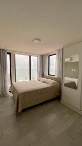 a bedroom with a bed and some windows at Apartamento Praia de Carapibus in Conde