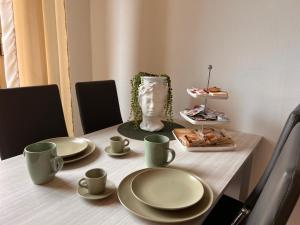 una mesa con platos y tazas y una estatua de una cabeza en Gambero Bianco, en Piano di Follo