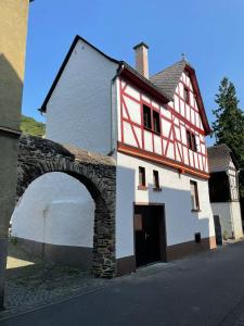 a white and red building with an archway next to a street at Fachwerk-Romantik 2 an der Mosel in Treis-Karden