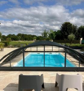 a swimming pool with a roof over a patio at Le Chai des Annereaux in Saint-Sulpice-de-Cognac