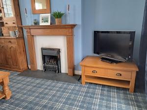 a living room with a fireplace and a television on a table at Seven Bays Stays in Saint Merryn