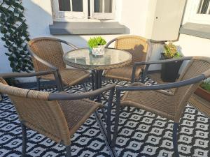 a glass table and chairs on a patio at Seven Bays Stays in St Merryn