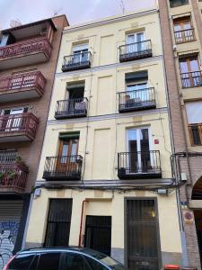 a building with balconies and a car parked in front of it at San Bernabé, apartamento para 2 en las Vistillas junto a metro Puerta de Toledo in Madrid