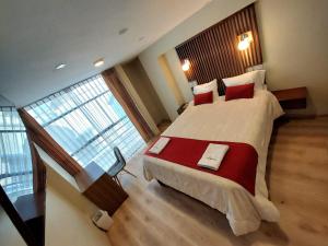 um quarto grande com uma cama grande e almofadas vermelhas em Hotel California em Juliaca