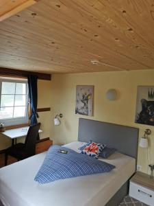 a bedroom with a bed with a desk and a window at Gasthaus Fuchsacker in Degersheim