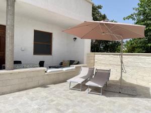 un patio con 2 sillas y una sombrilla en Villa Berenice, en Pachino