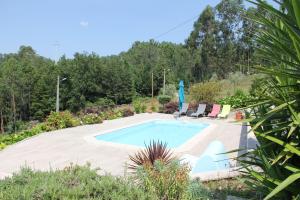 a swimming pool in a garden with two chairs and a umbrella at Casa Quelha da Presa in Espinho