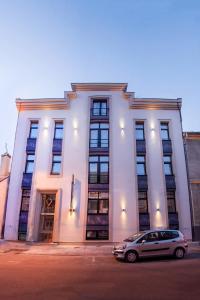 un edificio blanco con un coche aparcado delante de él en Caro Boutique Hotel, en Oradea