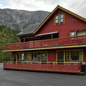 a large red building with a large balcony at Kvamsdal Pensjonat 1 in Eidfjord +5 photos