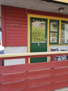 a red house with a green door and a window at Kvamsdal Pensjonat 1 in Eidfjord